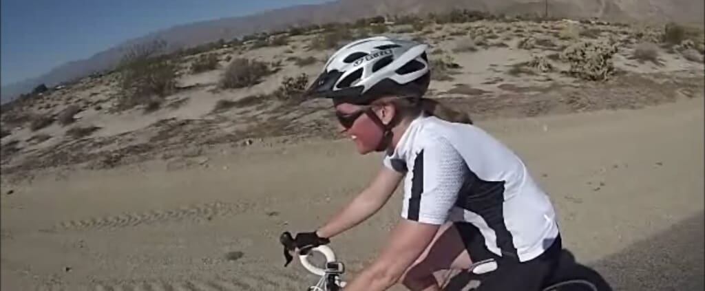 A woman riding a bike down a sandy road