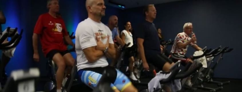 A group of people riding stationary bikes in a gym