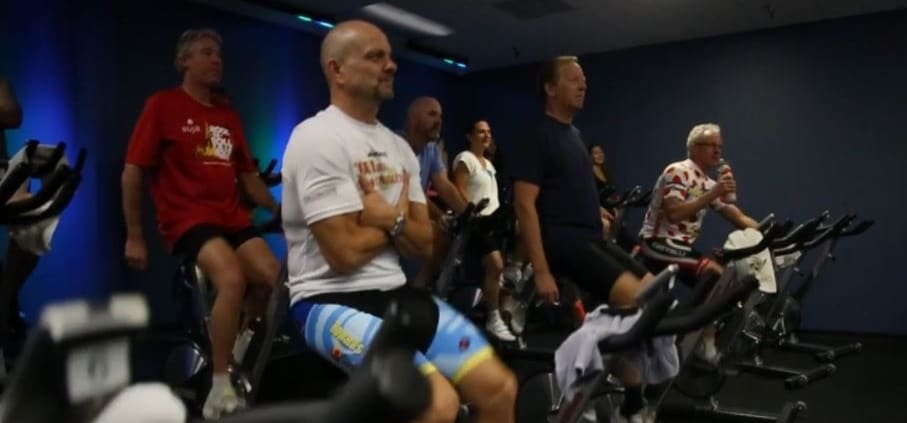 A group of people riding stationary bikes in a gym