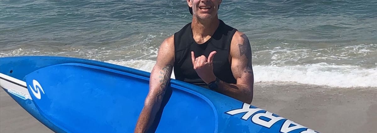 A man standing on a beach holding a surfboard