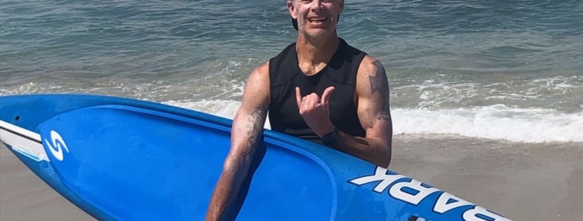A man standing on a beach holding a surfboard