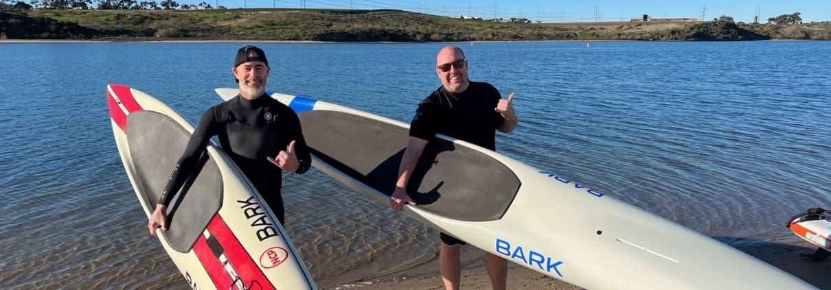 A couple of men standing next to each other holding surfboards