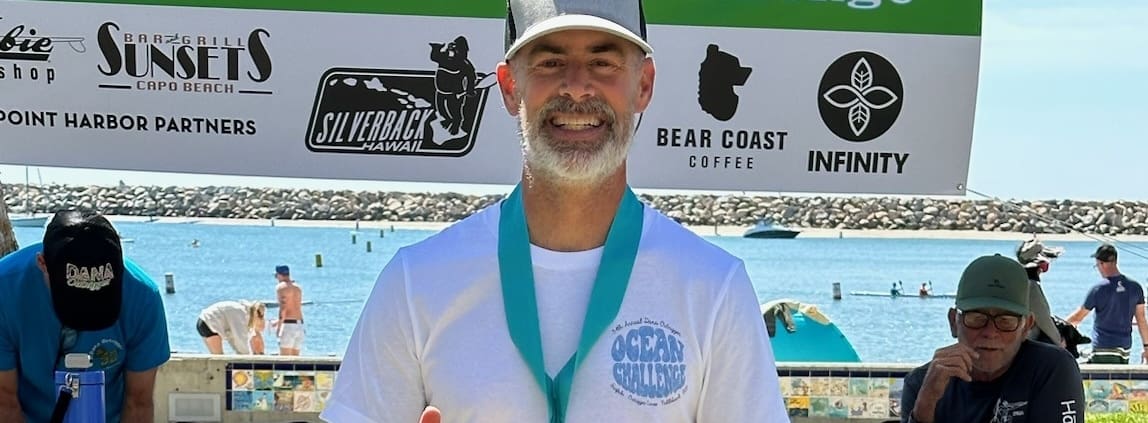 A man standing in front of a sign with a medal around his neck